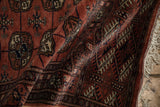 Close-up on the plush terracotta pile, fine weave, and ivory fringe of a Bokhara rug.