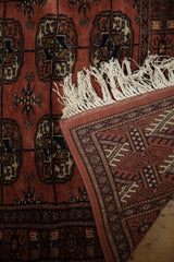 A vintage Bokhara rug's corner reveals its fine hand-knotted back, plush pile, and ivory fringe.