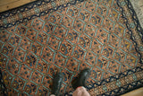 A vintage Ardebil rug's detailed lattice pattern of serrated leaves in rust and blue.