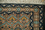 Corner of a vintage Ardebil rug with plush pile, a navy border with botehs, and ivory fringe.