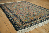 Vintage Persian Ardebil rug at an angle, displaying the geometric lattice field and navy border.