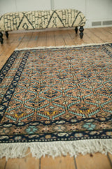 Angled view of a vintage Ardebil rug, showing its plush pile and geometric lattice pattern.