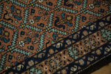 Serrated leaf and floral motifs on a vintage Ardebil rug's rust-colored field and navy border.