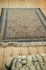 Dense, full pile of a vintage Ardebil rug, showing its rust and blue lattice design and ivory fringe.