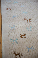 Folk art pictorial animals in silver-gray and brown art silk on a beige textured pile.