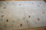 Teal and dark brown art silk animals on a textured beige Indian folk art carpet.