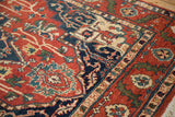 Serrated leaf and floral blossoms in the vintage rug's terracotta and blue border.