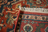 Folded corner of the vintage Heriz design carpet showing its hand-knotted back, selvage, and fringe.