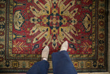 A close perspective showing the full pile of a vintage Kazak rug in rust and navy blue.