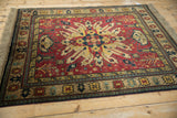 Vintage Kazak design rug with a central starburst medallion in rust, ivory, and navy, seen from above.