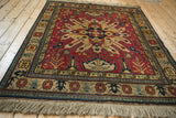 A vintage square Kazak rug shown from an angle, highlighting its geometric starburst medallion and fringe.