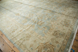 Corner of vintage Indian Oushak rug with beige border and powder blue floral motifs.