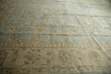 Detailed view of the Oushak carpet's beige border with delicate vinery and floral motifs.