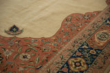 Close-up of the vintage carpet's corner showing the floral spandrel, finial, and navy border.