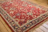 A vintage Agra carpet seen from an angle, highlighting the lustrous cherry red wool pile and intricate floral design.