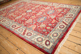 Angled view of a vintage Indian Heriz carpet, showcasing its lustrous cherry red wool pile and ivory border.