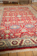 Angled view of the cherry red field and geometric floral pattern on a vintage Indian carpet.