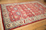 Vintage Indian carpet viewed at an angle, showing the repeating geometric floral design on a cherry red field.