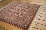 Dusty rose vintage Bokhara rug showcasing intricate border patterns and intact fringe.