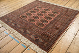 Ivory fringe and dusty rose border with geometric patterns on a vintage Bokhara rug.