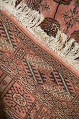 Intact dusty rose side cord selvage, ivory fringe, and navy geometric Bokhara pattern.