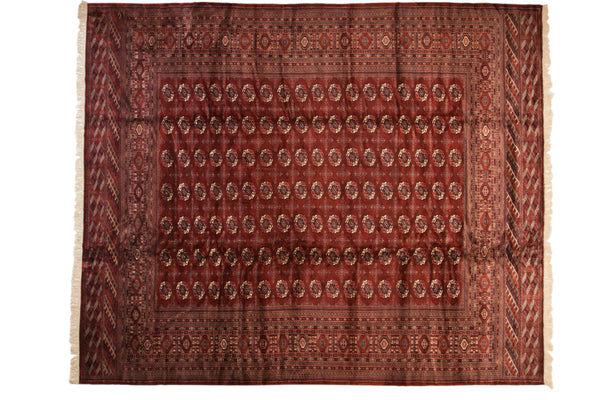 Vintage Bokhara carpet with a dense, repeating pattern of gul medallions in wine red, navy, and ivory.