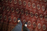 The plush, wine-red wool pile of a fine Bokhara rug, highlighting its soft, hand-knotted texture.