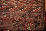 Finely woven corner of a vintage Bokhara carpet with geometric gul medallions and intricate borders.