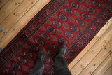 Standing on a plush red Bokhara runner, showing its repeating gul medallion pattern and scale.