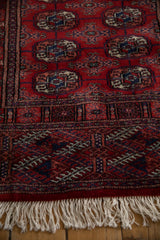 Intricate hand-knotted border and ivory fringe on a red vintage Bokhara rug runner.