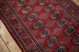 Intricate navy and ivory gul medallions repeating across the red wool pile of a Bokhara rug.