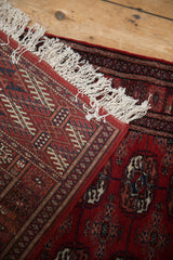 A folded corner of a vintage Bokhara rug runner reveals its fine hand-knotted back weave and plush red pile.