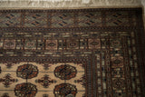 Corner of a vintage Bokhara rug with plush pile, detailed geometric borders, and ivory fringe.