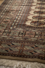 Side angle view of a vintage Bokhara carpet's lustrous pile, intricate geometric borders, and fringe.