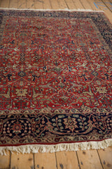 Angled view of a vintage Agra carpet's plush texture, deep navy border, and red field pattern.