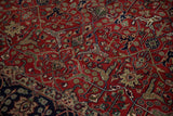 Hand-knotted Samovar motifs in brick red alongside the carpet's navy blue vinery border.