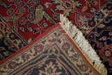 Corner of a vintage Agra carpet displaying its full pile, floral border, and clean ivory fringe.