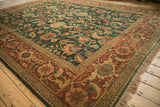 Angled view of a vintage Serapi carpet's lustrous green pile and terracotta turtle border.