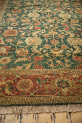 A close-up view of the vintage carpet's terracotta border and deep green field with floral vinery.