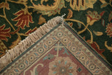 Folded corner of a vintage Indian rug displays its hand-knotted reverse, ivory fringe, and green pile.