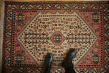 Vintage Persian Abadeh rug with a salmon geometric medallion on a beige field with blue accents.