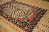 Angled view of a vintage Abadeh rug with a geometric field and terracotta floral border.