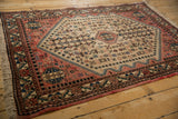 Angled view of a distressed Abadeh rug's corner, with floral borders in salmon pink and blue.