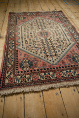 Full perspective view of a vintage Abadeh rug with its geometric medallion in pink and blue.