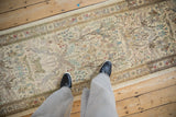 Scale view looking down at a vintage Tabriz runner with a soft, pictorial forest scene.