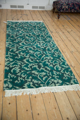 Angled view of the vintage runner, highlighting the carved texture of its green leaf pattern.