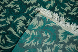 Carved pile texture and hand-knotted foundation of a vintage green rug runner.