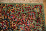 Vintage Kerman carpet corner: celadon green, blush, sky blue floral sprays and fringe.