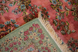 Blush floral pile, cream fringe, and celadon green hand-knotted back of a vintage Kerman rug.