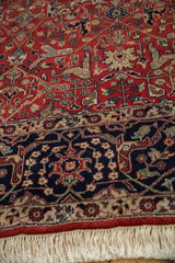 Navy blue border, scrolling vinery, brick red field, and creamy white fringe.